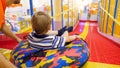 Cute little boy riding down the slide on inflatable donut ring in child`s playing room at shopping mall Royalty Free Stock Photo
