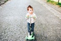 Pretty little boy riding scooter outdoor on the street Royalty Free Stock Photo