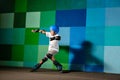 Cute little boy on roller skates running against the blue graffiti wall