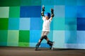 Cute little boy on roller skates running against the blue graffiti wall