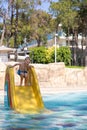 Cute little boy rolls down a water slide in a aquapark. Activities in the pool. Concept summer vacation, rest, fun Royalty Free Stock Photo