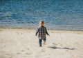 Cute little boy runing on sandy beach. Rear view