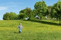 Cute little boy running across grass und smiling outdoors in a public park garden. young kid having fun outside making a run Royalty Free Stock Photo