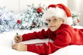 cute little boy in Santa Claus hat writes letter to Santa Claus to get gift lying on bed against background of Christmas Royalty Free Stock Photo