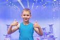 Cute little boy is showing thumb up sign on blue background. Excited kid having fun at zoo park Royalty Free Stock Photo