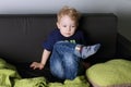 Cute little boy sits and thinks on black couch