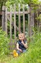 Cute little boy sitting on the background of a rustic wooden fence Royalty Free Stock Photo