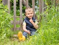 Cute little boy sitting on the background of a rustic wooden fence Royalty Free Stock Photo