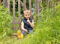 Cute little boy sitting on the background of a rustic wooden fence Royalty Free Stock Photo