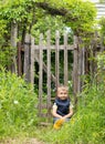 Cute little boy sitting on the background of a rustic wooden fence Royalty Free Stock Photo