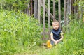 Cute little boy sitting on the background of a rustic wooden fence Royalty Free Stock Photo