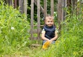 Cute little boy sitting on the background of a rustic wooden fence Royalty Free Stock Photo