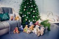 Cute little boy sitting down by the decorated Christmas tree with toys, teddy bears and gift boxes Royalty Free Stock Photo