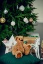 Cute little boy sitting down by the decorated Christmas tree with toys, teddy bears and gift boxes Royalty Free Stock Photo