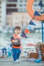 Cute little boy sitting on the floor on pier outdoor, a marine style. Little sailor Royalty Free Stock Photo