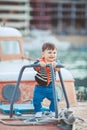 Cute little boy sitting on the floor on pier outdoor, a marine style. Little sailor Royalty Free Stock Photo