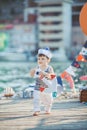 Cute little boy sitting on the floor on pier outdoor, a marine style. Little sailor Royalty Free Stock Photo