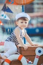 Cute little boy sitting on the floor on pier outdoor, a marine style. Little sailor Royalty Free Stock Photo