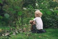 Cute little boy sitting on the lawn in the Park and thinks about life. Children`s loneliness concept