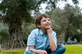 Cute little boy sitting in the park smiling thinking Royalty Free Stock Photo