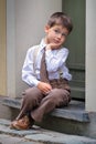 Cute little boy sitting on porch outdoors in city