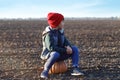 Cute little boy sitting on pumpkin in autumn field Royalty Free Stock Photo