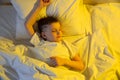 Cute little caucasian boy sleeping in his comfortable bed in the morning under yellow sun light. Good morning Royalty Free Stock Photo