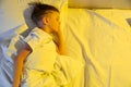 Cute little caucasian boy sleeping in his comfortable bed in the morning under yellow sun light. Good morning Royalty Free Stock Photo