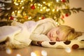 Cute Little Boy Sleeping Under The Tree On Christmas Eve. Child Waiting Santa Claus. Baby Hopes Of Magic And Gifts At Christmas