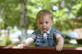 Cute little boy standing in the park on a bench standing and looking thoughtfully at the camera Royalty Free Stock Photo