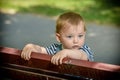 Cute little boy standing in the park on a bench standing and looking thoughtfully at the camera Royalty Free Stock Photo