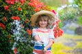 Cute little boy in straw hat is laughing with water spraying hose. Royalty Free Stock Photo