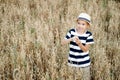 Cute little boy in a straw hat is sitting on an oat field playing hide and seek. Funny kid hiding in a field with oats. Royalty Free Stock Photo