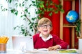 Cute little boy studying at home using tablet laptop computer. Child boy in glasses looking at camera and smiling. Back Royalty Free Stock Photo