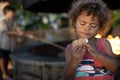 Cute little boy about to eat a s`more while sitting by an outdoor fire