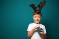 Cute little boy with toy reindeer horns holding cup of hot chocolate on color background Royalty Free Stock Photo