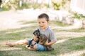 Cute little boy and two puppies sitting and playing on the grass in summer Royalty Free Stock Photo