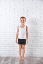 Cute little boy in underwear near white wall