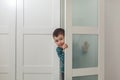 Cute little boy in wardrobe at home. Peeking, hiding, playing Royalty Free Stock Photo