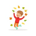 Cute little boy in warm clothing jumping and throwing autumn leaves up, lovely kid enjoying fall, autumn kids activity