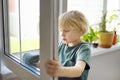 Cute little boy washing a window at home. Child helping parents with household chores, for example, cleaning windows in his house Royalty Free Stock Photo