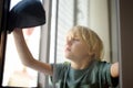 Cute little boy washing a window at home. Child helping parents with household chores, for example, cleaning windows in his house Royalty Free Stock Photo