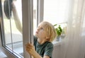 Cute little boy washing a window at home. Child helping parents with household chores, for example, cleaning windows in his house Royalty Free Stock Photo