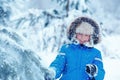 Cute little boy wearing warm clothes playing on winter forest Royalty Free Stock Photo