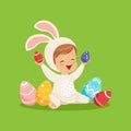 Cute little boy in a white bunny costume playing with colorful painted eggs, kid having fun on Easter egg hunt vector