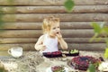 Cute little boy eats berries and cup of milk on wooden background Royalty Free Stock Photo