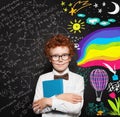 Cute little boy in white shirt and bow tie posing in front of blackboard. Portrait of smart male child. Smiling school boy