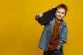 Cute little boy 6-7 years old, in stylish clothes, holding a skateboard in his hand, isolated on a yellow Royalty Free Stock Photo