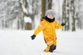 Cute little boy in yellow winter clothes walks during a snowfall