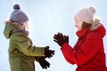 Cute little boy and young mother playing snowballs together during stroll in snowy winter park. Family winter fun in the fresh air Royalty Free Stock Photo